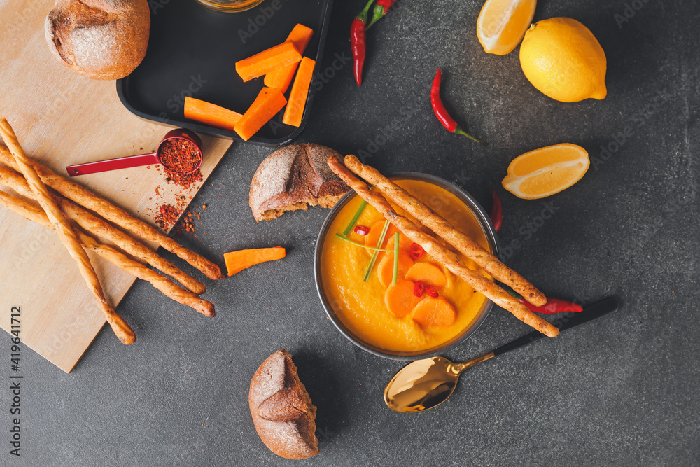 Composition with tasty carrot cream soup on dark background