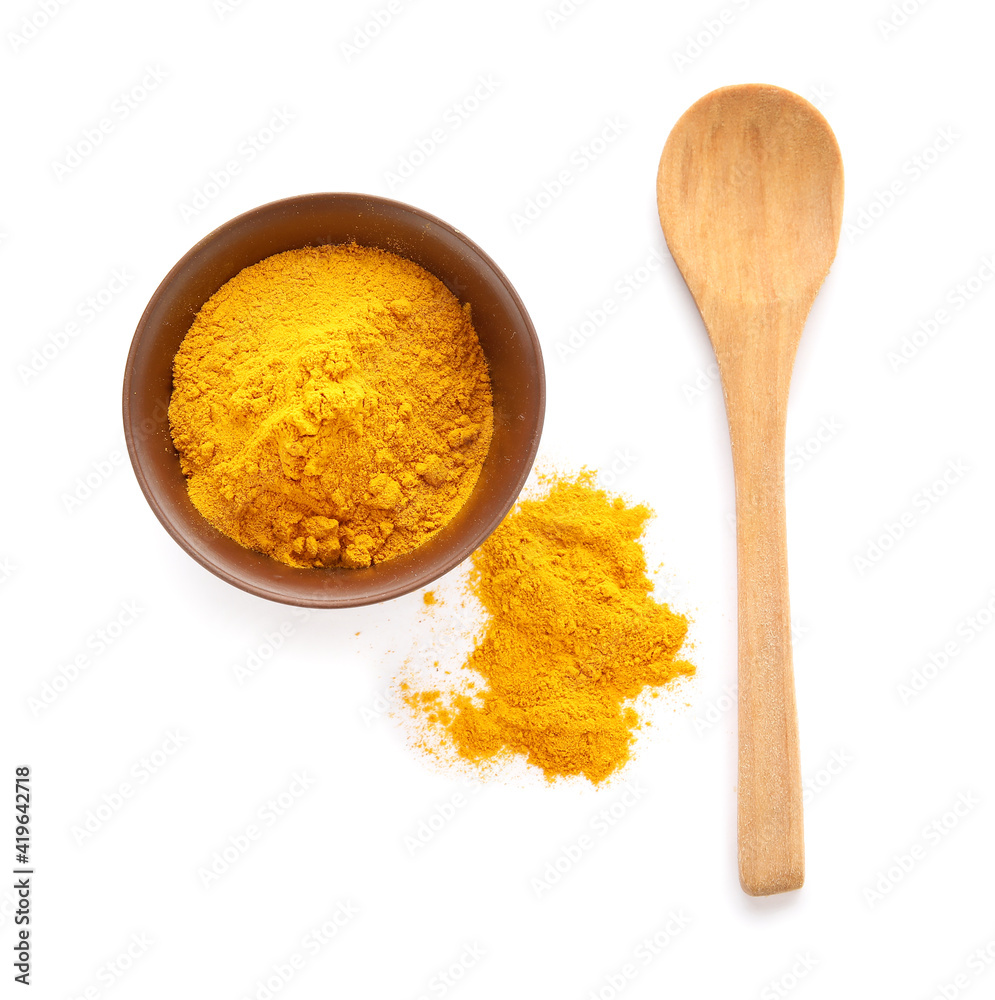 Bowl with turmeric powder and spoon on white background