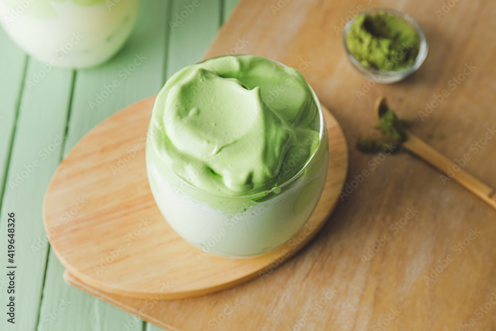 Composition with tasty dalgona matcha latte on color wooden background, closeup