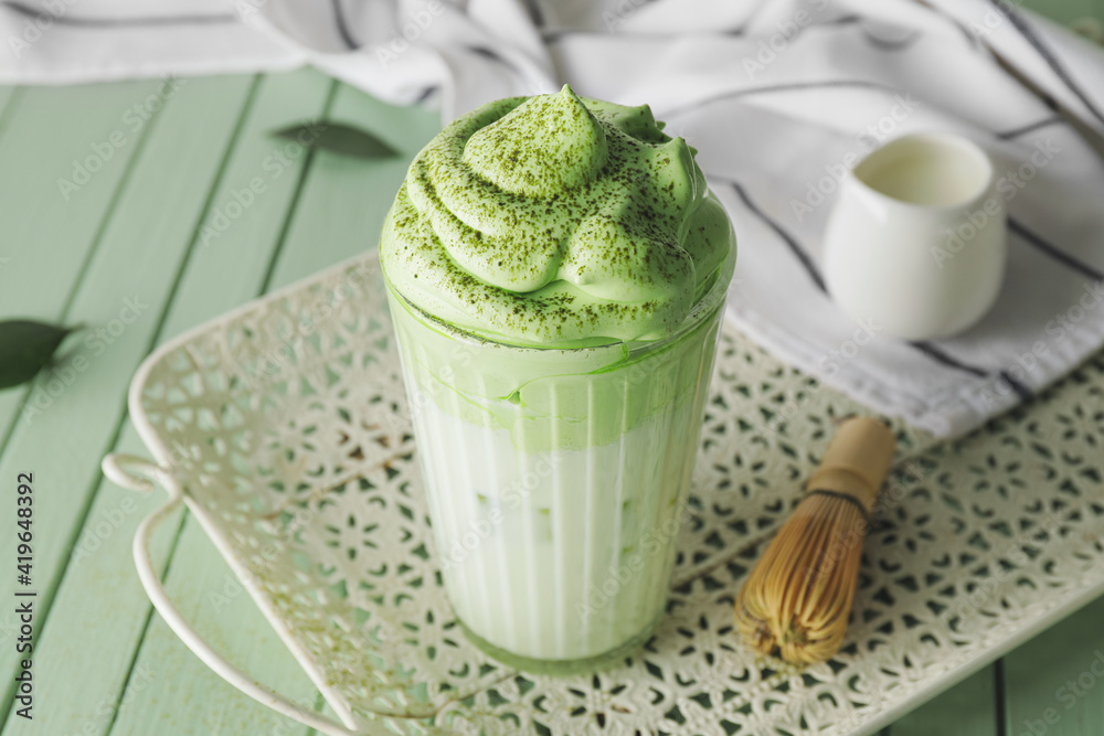 Composition with tasty dalgona matcha latte on color wooden background