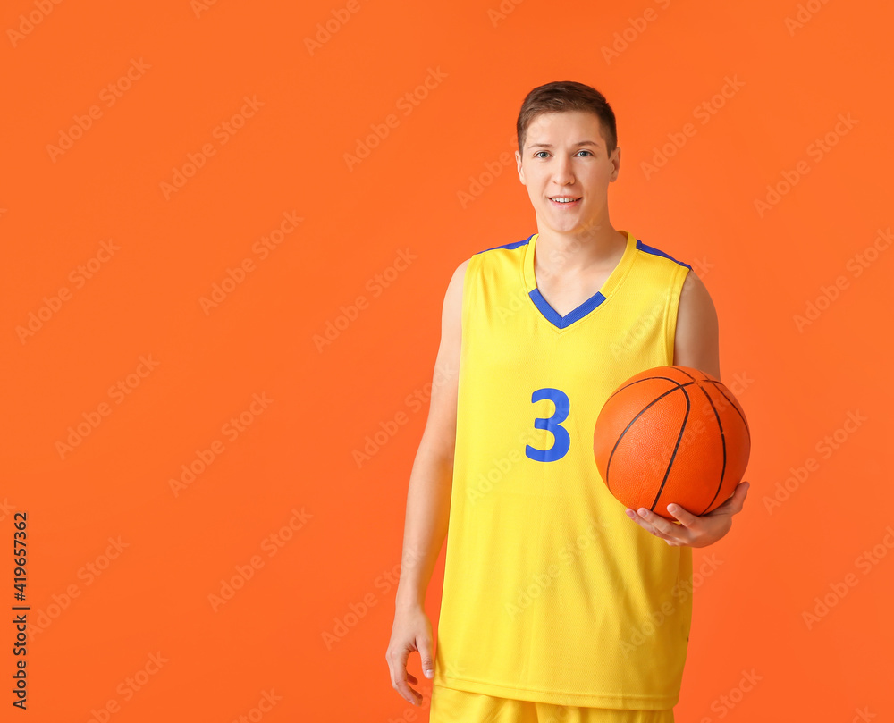 Handsome young man with ball on color background