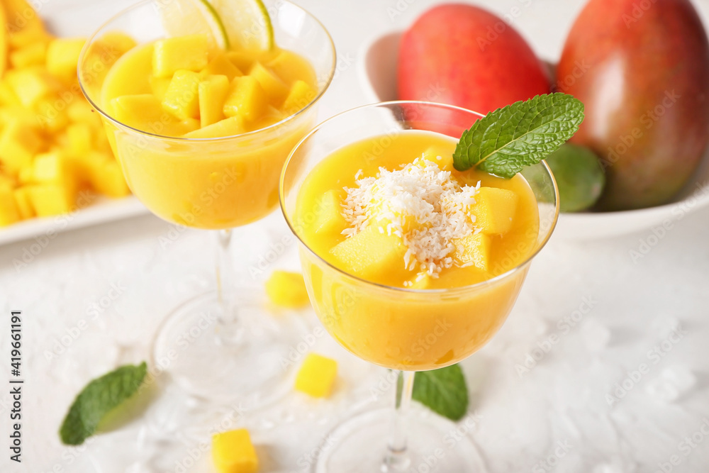 Glasses of mango margarita on light background