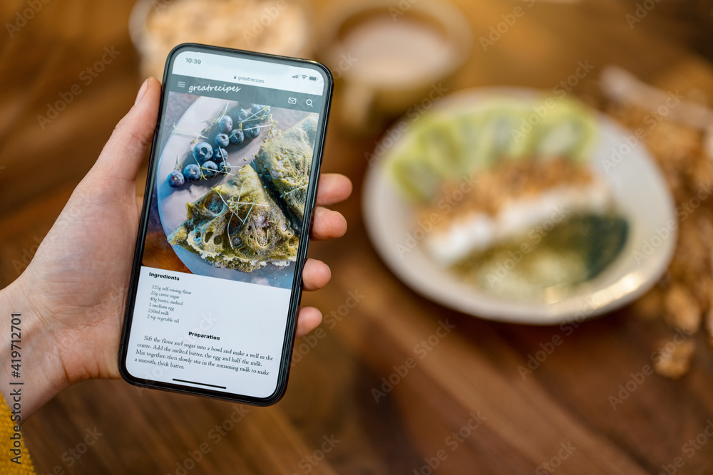 Digital recipe of healthy breakfast with pancake on the phone screen on wooden table top in kitchen 