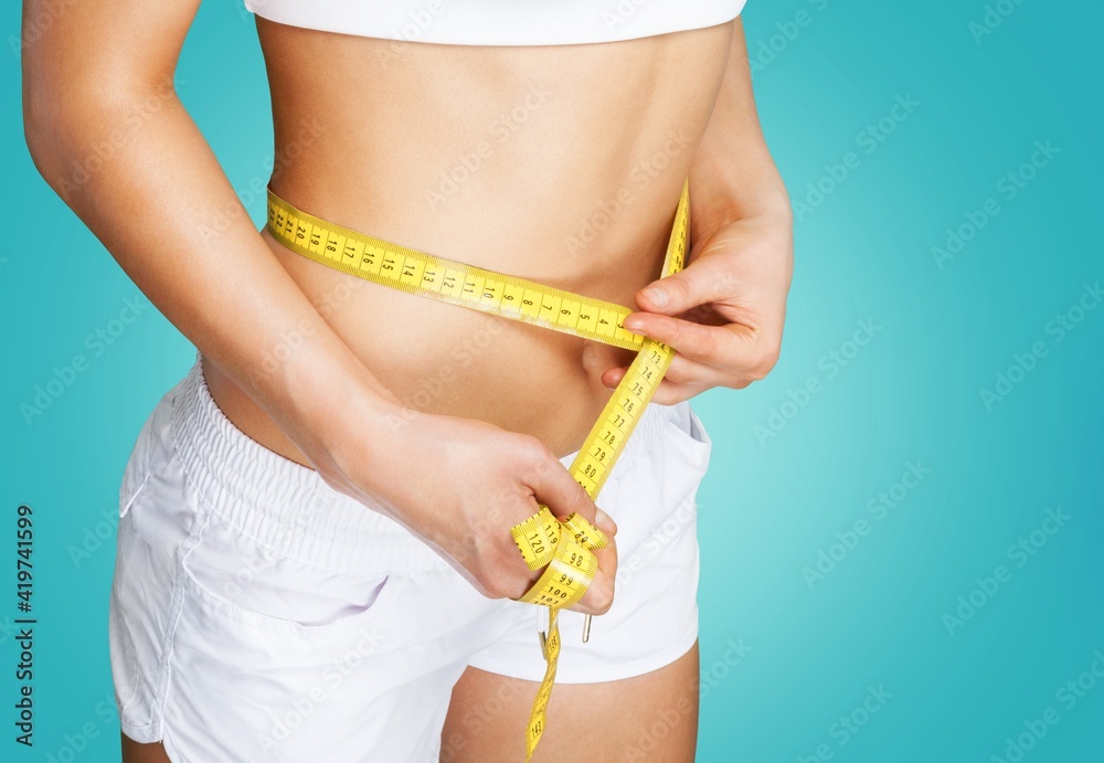 Slim young woman measuring her thin waist