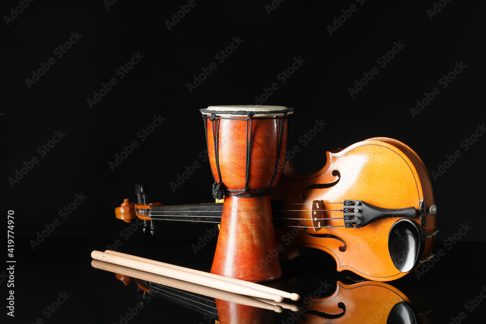 Wooden djembe, violin and drumsticks on dark background