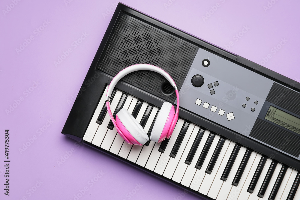 Modern synthesizer and headphones on color background