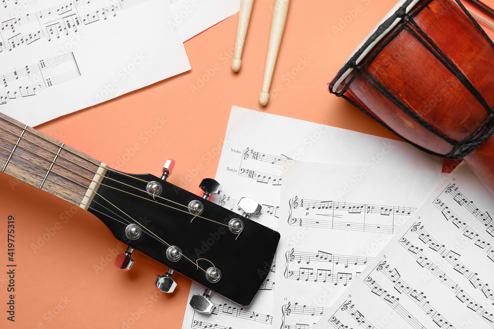 Acoustic guitar, drumsticks, djembe and music notes on color background, closeup