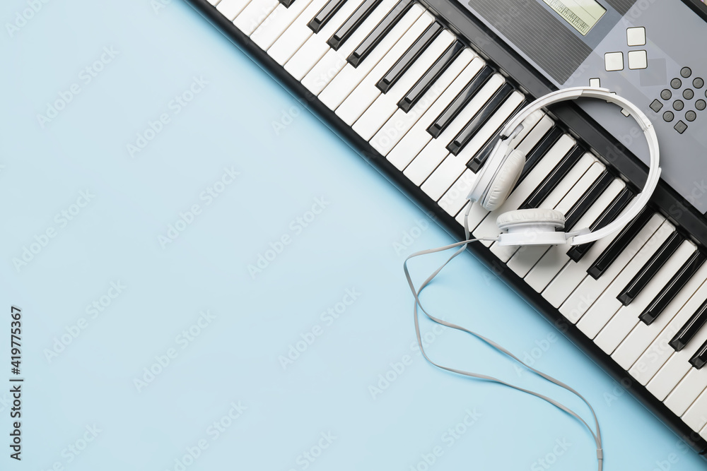 Modern synthesizer and headphones on color background