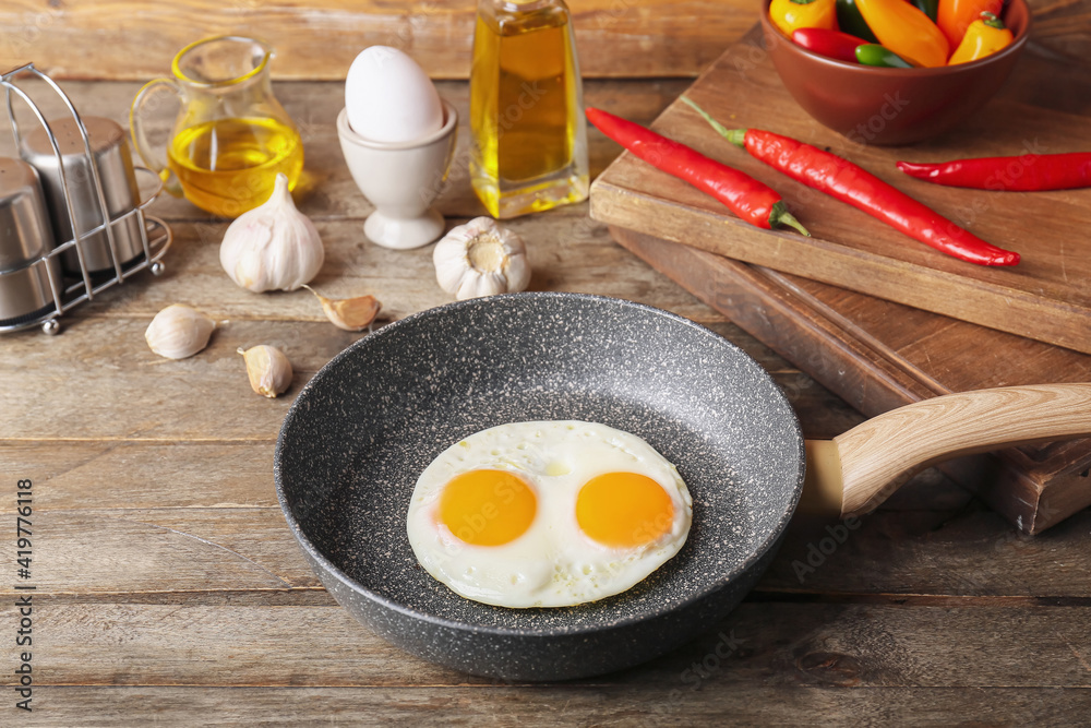 Frying pan with tasty eggs on wooden background