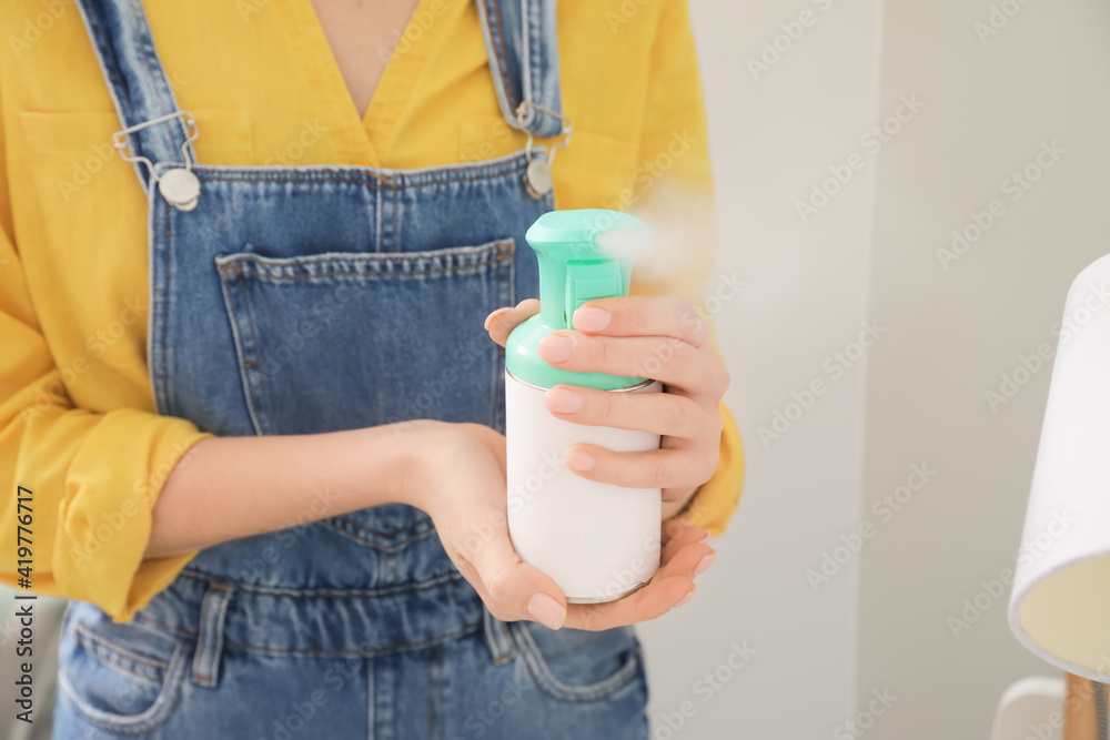 Young woman with air freshener at home, closeup