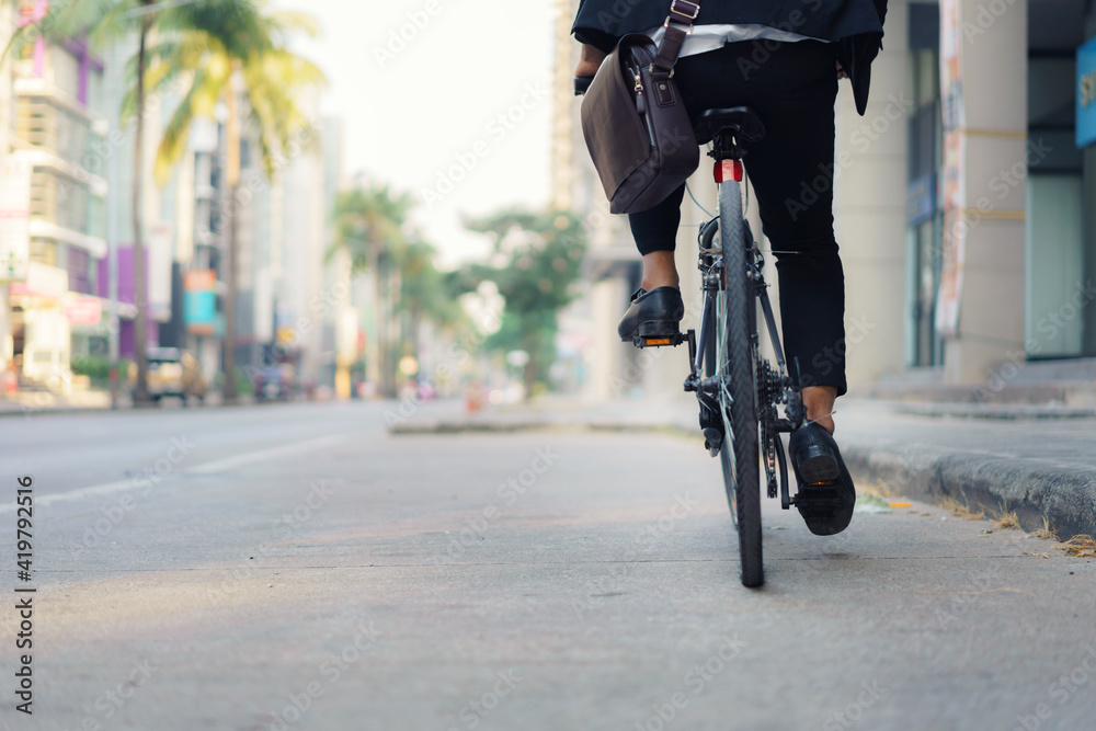 Close up of foot businessman is riding a bicycle on the city streets for his morning commute to work