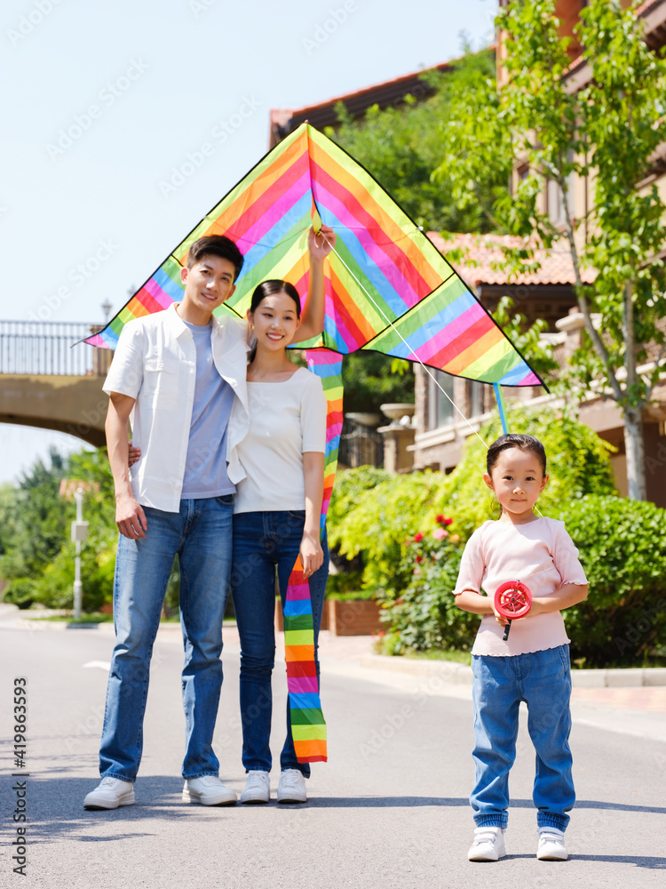 Happy family of three flying kites outdoors