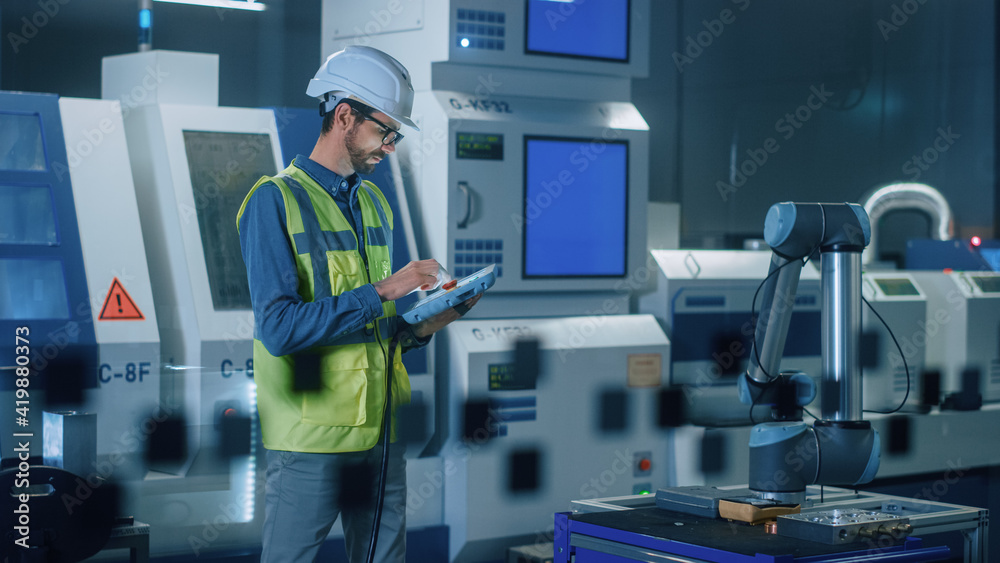 Portrait of Professional Engineer Wearing Safety Vest and Hardhat, Uses Industrial Digital Tablet to