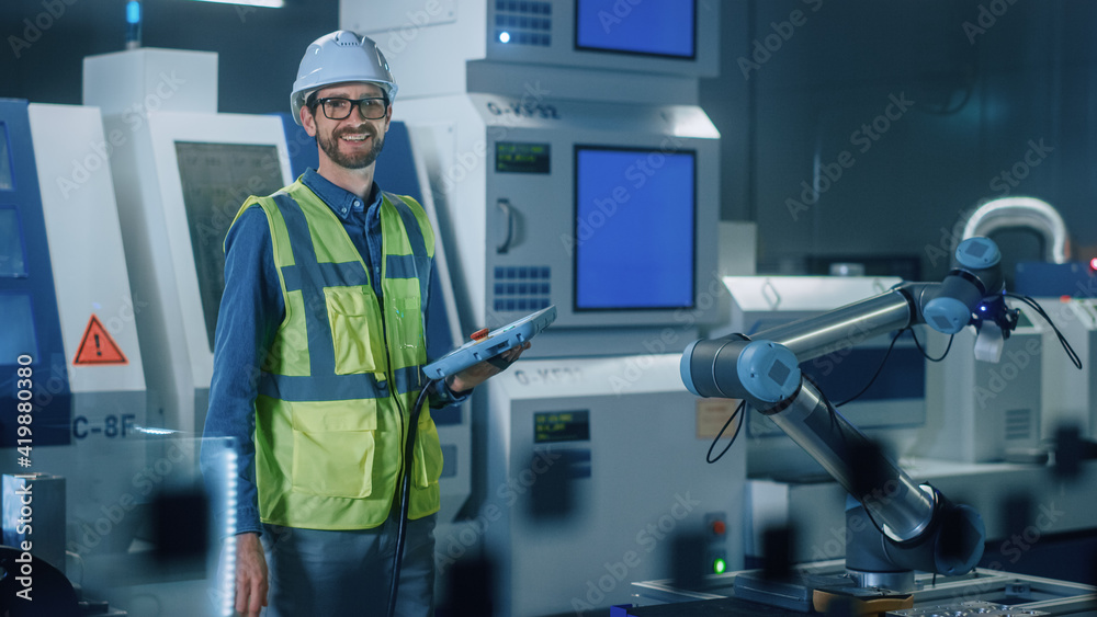 Portrait of Professional Engineer Wearing Safety Vest and Hardhat, Uses Industrial Digital Tablet to