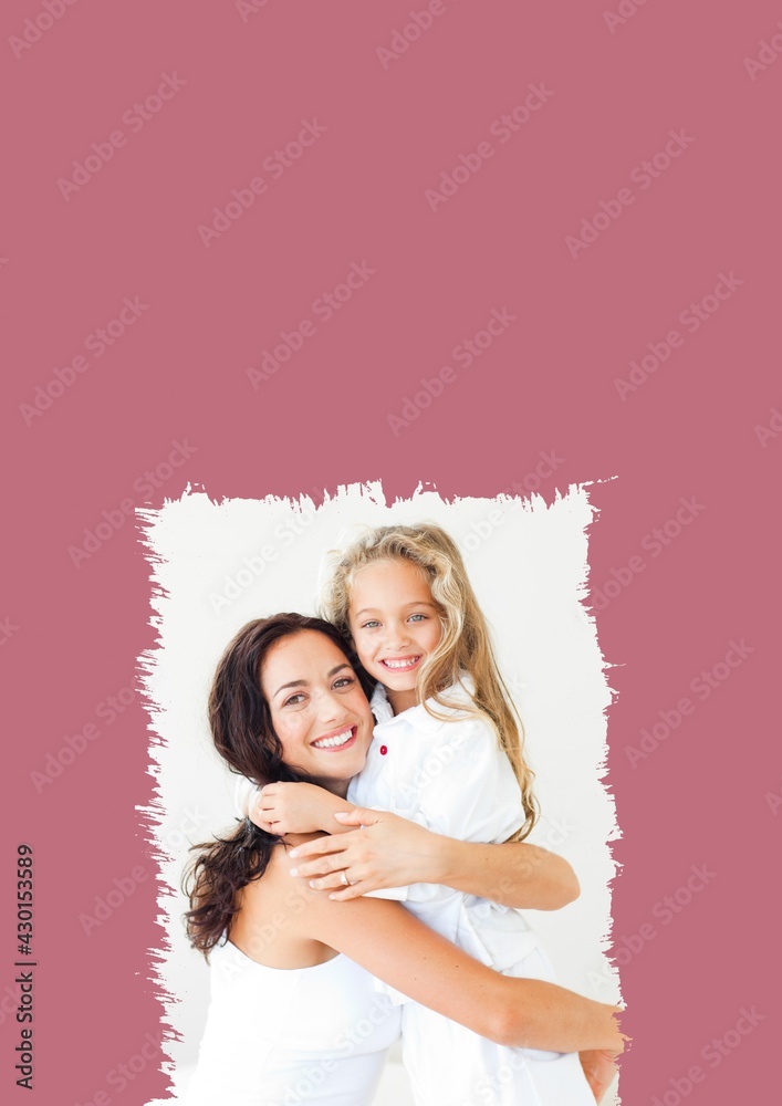 Portrait of smiling mother and daughter hugging with copy space on pink background