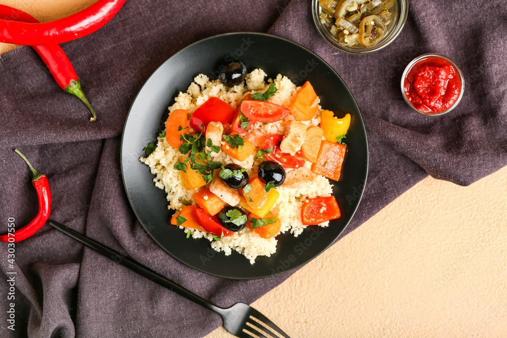 Plate with couscous and vegetables on color background