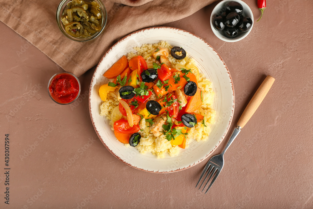 Plate with couscous and vegetables on color background