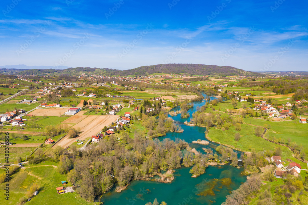 Mreznica river in Croatia from air, drone view of Belavici village in spring