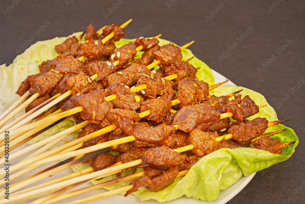 Grilled beef kebabs on a white plate, street food