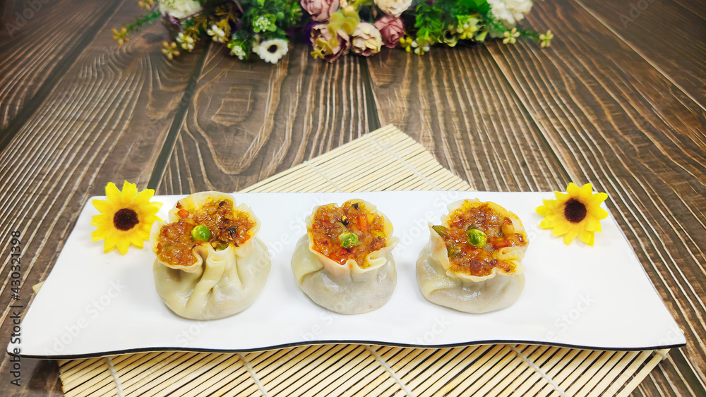 3 Shumai on white dish on bamboo mat with 2 sunflowers, wooden texture background, traditional Chine