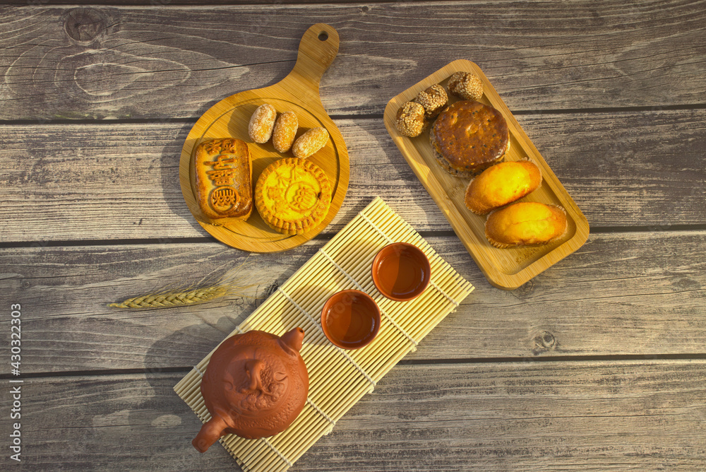 Various desserts on wooden cutting board like moon cakes, egg yolk pies and sesame balls, etc.  A pu