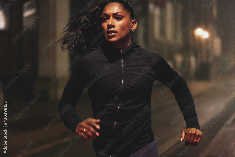 Young woman running in the city at night