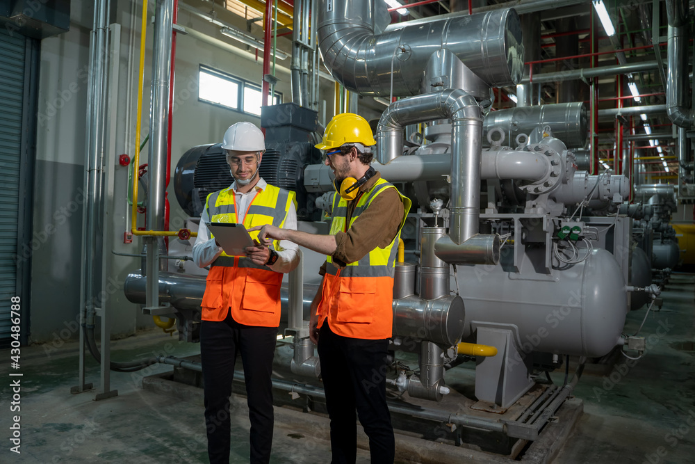 Two engineers working and checking information in a factory,They work a heavy industry manufacturing