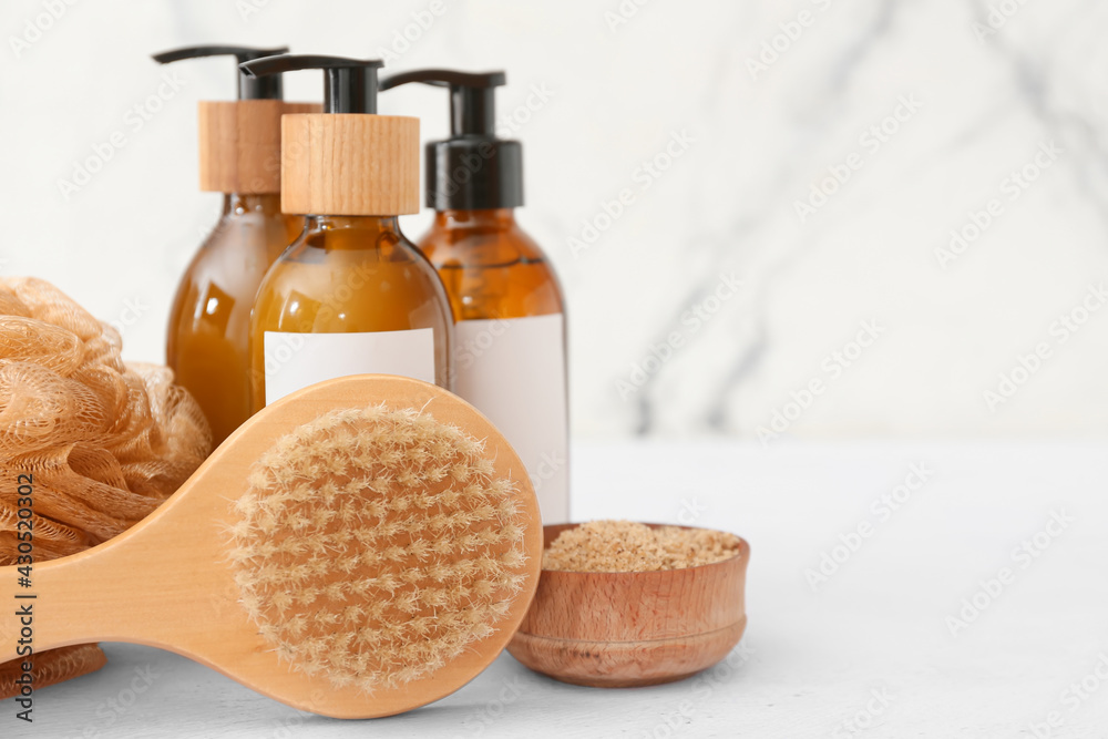 Composition with massage brush and bath supplies on light background, closeup