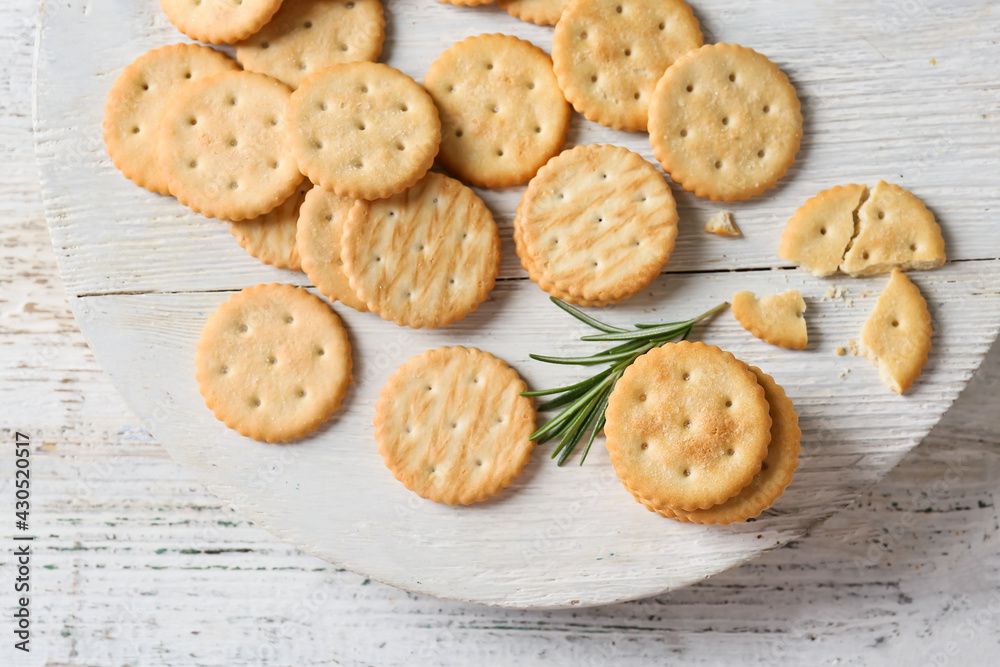 Board with tasty crackers on light wooden background