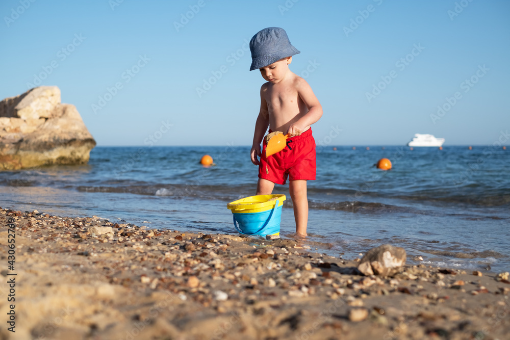 Boy kid in red shorts on the summer beach