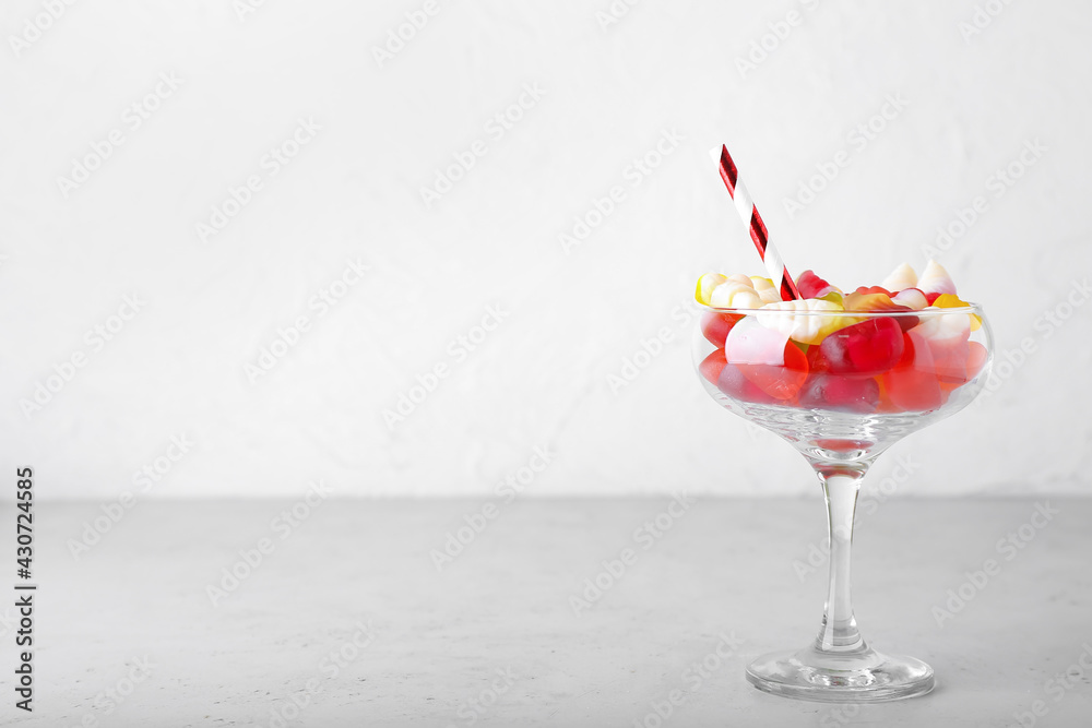 Glass of tasty jelly candies on light background