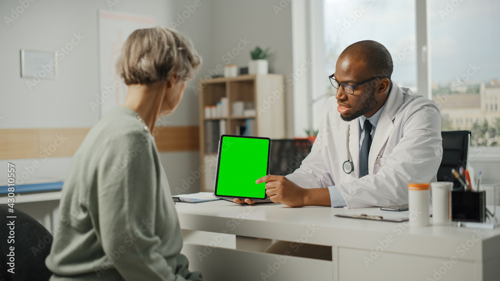 African American Family Doctor Showing Tablet Computer with Green Screen Display to Senior Female Pa