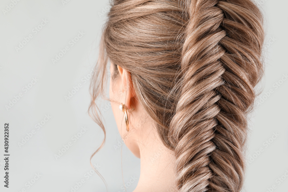 Beautiful young woman with braided hair on grey background, closeup