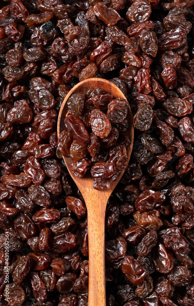 Wooden spoon on top of a grape-raisin in the background