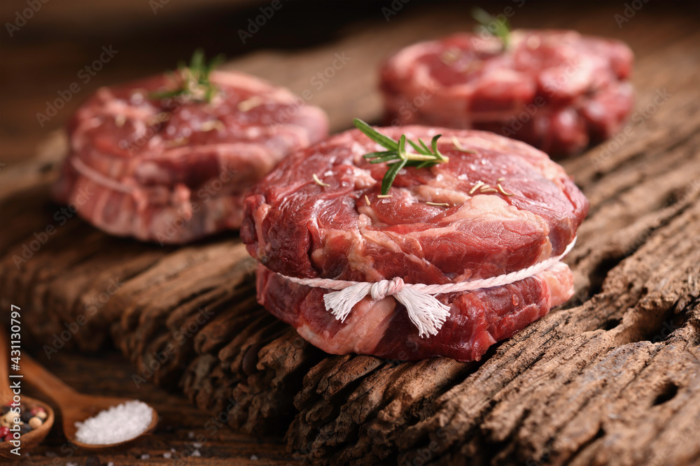 Fresh raw pieces of beef meat on old wooden background