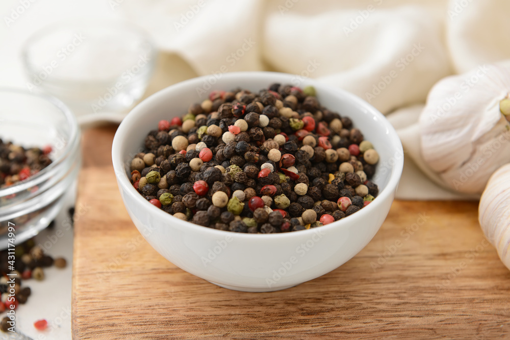 Bowl with peppercorns on wooden background