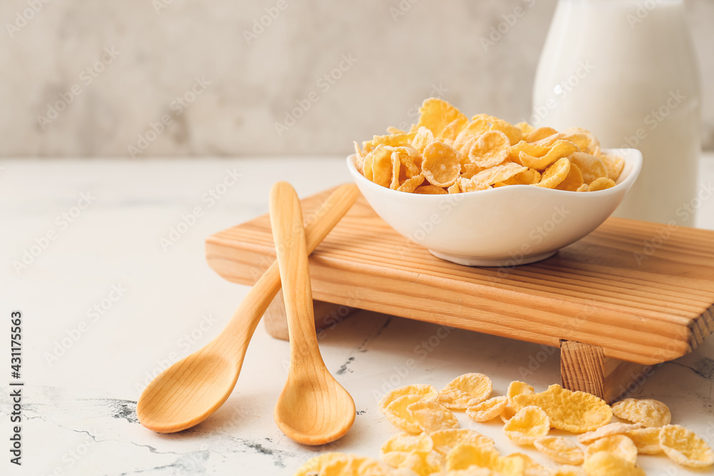 Bowl with tasty cornflakes on light background