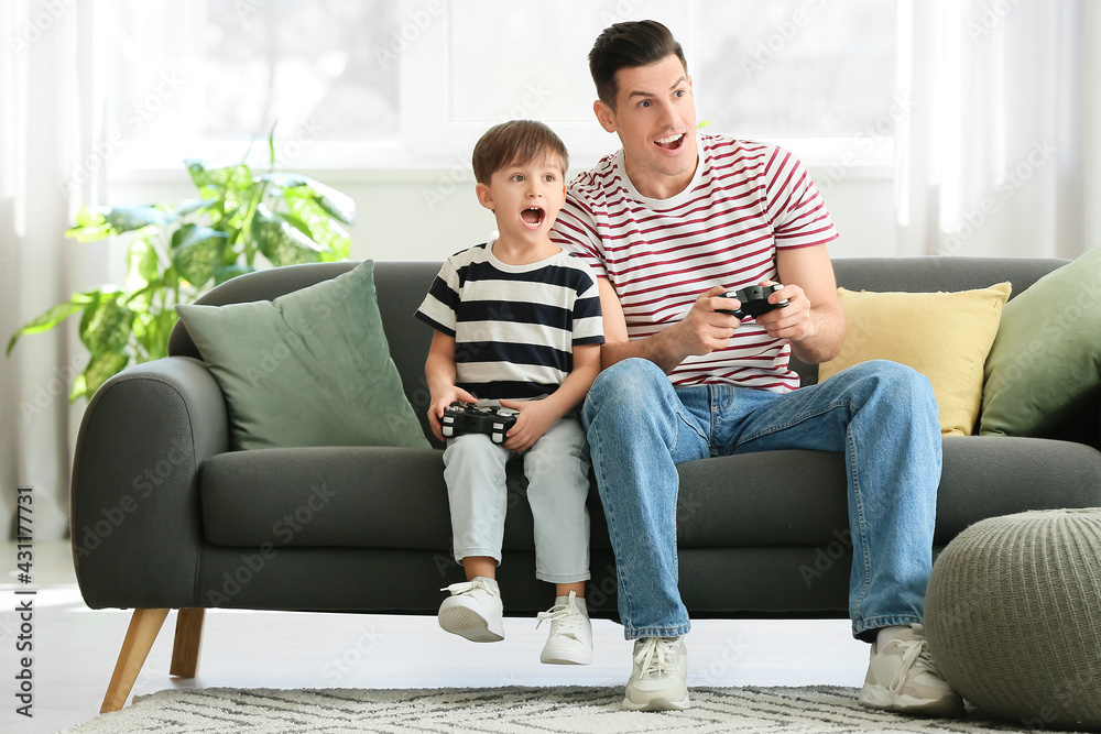 Father and his little son playing video game at home