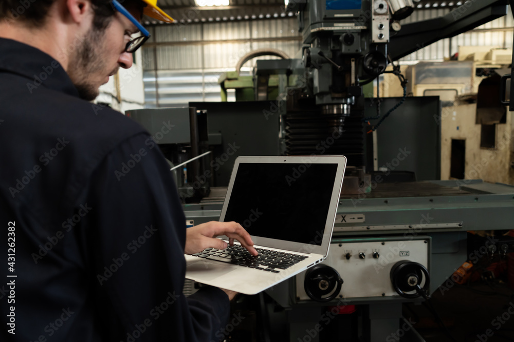 Skillful factory worker working with laptop computer to do procedure checklist . Factory production 