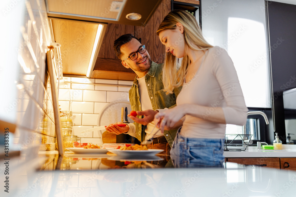 Time for lunch. Young couple is preparing lunch at kitchen. Man is helping to his girlfriend.