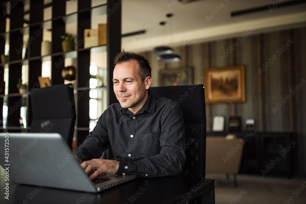 Handsome smiling businessman working on laptop, portrait.