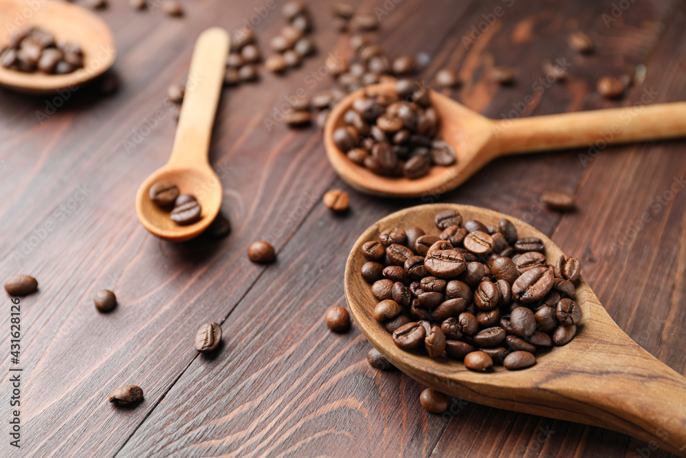 Spoons with coffee beans on wooden background