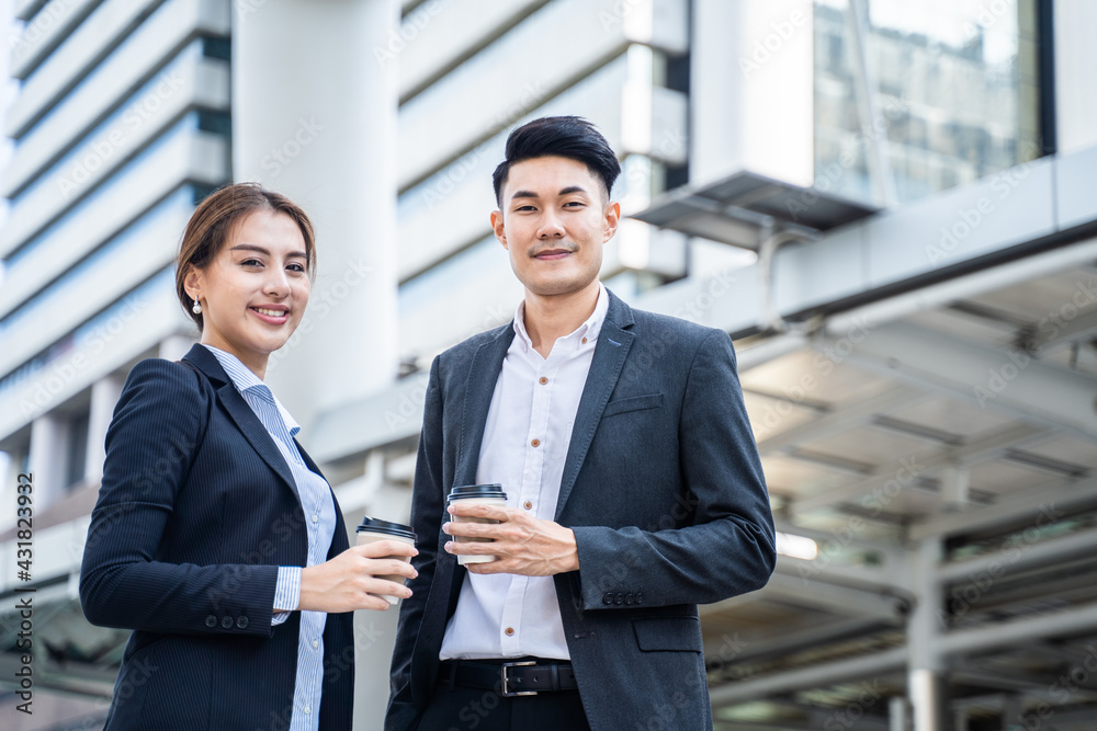 Asian young business people standing in the city, holding coffee cup.