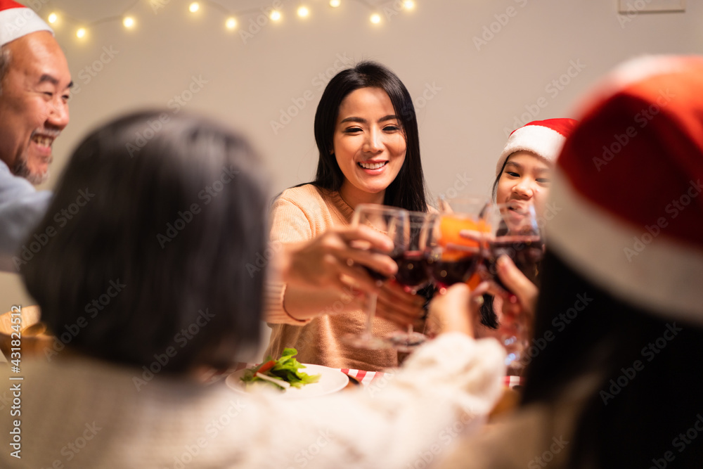 Asian big family clinking wine glasses and enjoying Christmas party.