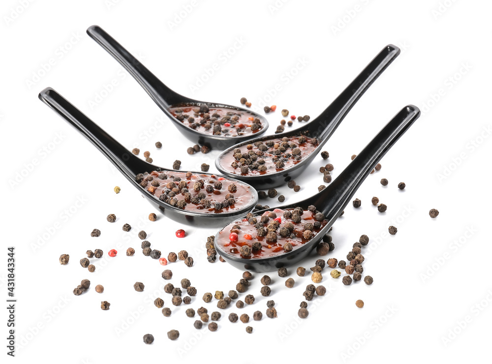 Spoons with peppercorn sauce on white background