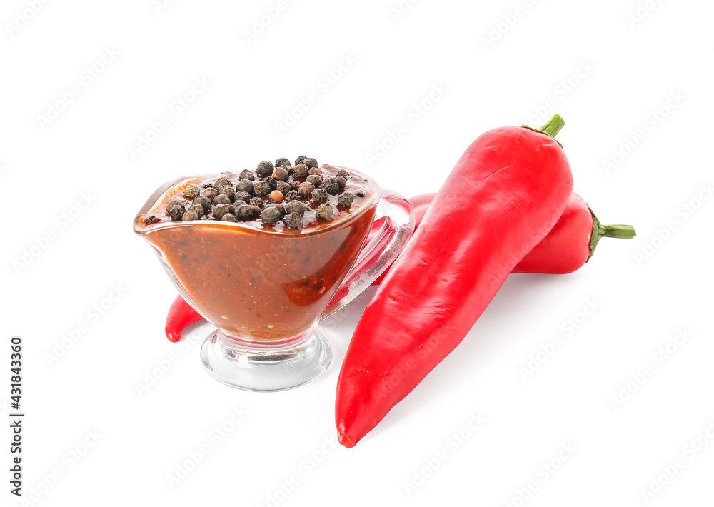 Gravy boat with peppercorn sauce and chili peppers on white background