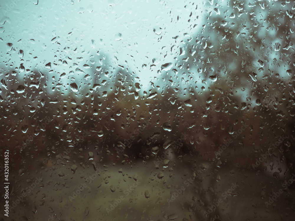 Raindrops on window with blurry background after spring rain