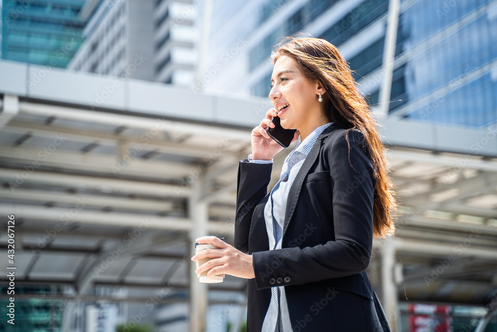 Asian businesswoman talking on the phone walking to office in the city