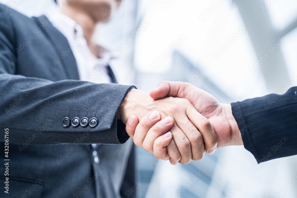 Close-up shot of Asian businessmen making handshake in the city.