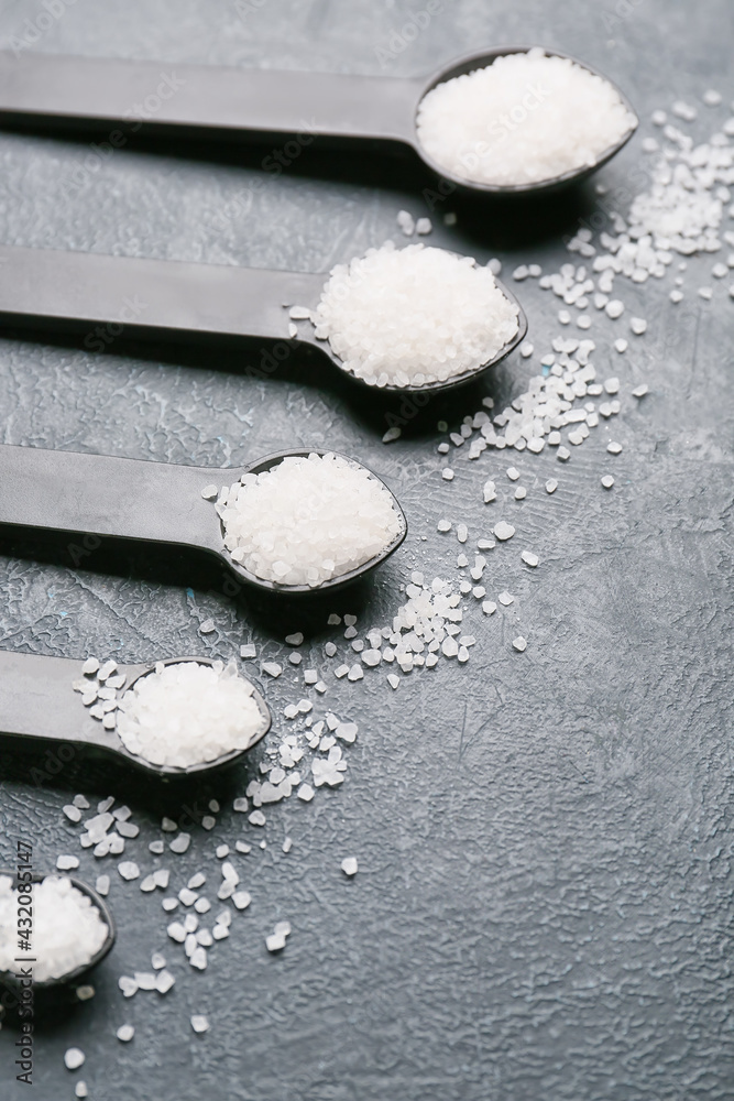 Measuring spoons with salt on dark background